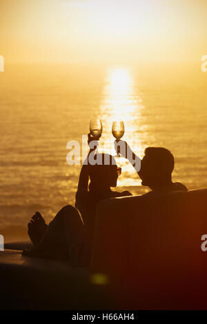 Silhouette paar Weingläser auf Balkon mit Blick auf den ruhigen Sonnenuntergang Ozean Toasten Stockfoto