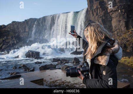 Touristen fotografieren und beobachten Sie den Wasserfall in Pingvellir Nationalpark bekannt als Oxarafoss vom Fluss Oxara. Stockfoto