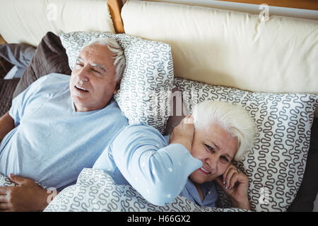 Schnarchen Mann und Frau für ihre Ohren während des Schlafens auf Bett Stockfoto