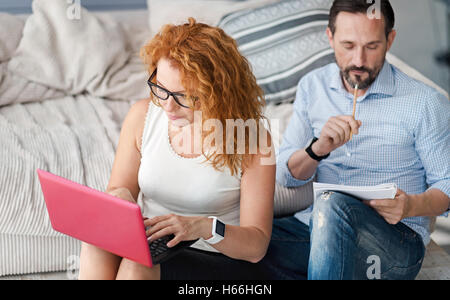 Frau mit Laptop beim Mann Notizen arbeiten Stockfoto