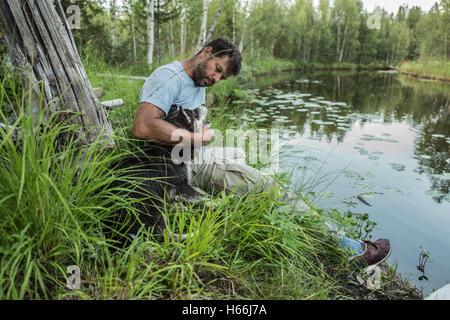 Man spielt mit dem Hund am Ufer des Sees Stockfoto