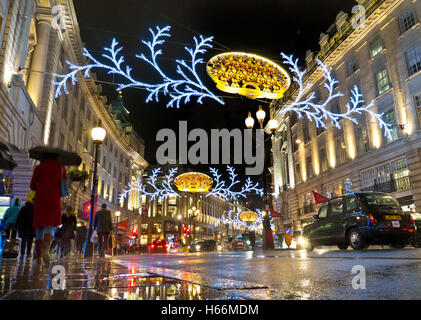 Belebten Szene Weihnachts-Shopper, Verkehr und Schirme in einem Regen fegte die Regent Street mit Weihnachtsbeleuchtung hinter London UK Stockfoto