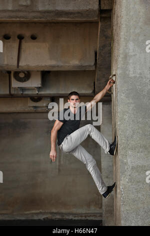 Männer T-shirt Parkour im urbanen Raum. Er klettert die Wand. Sport in der Stadt. Bewegung ist Leben. Stockfoto