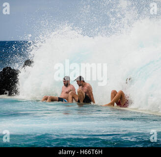 Drei Männer genießen Sie ein Bad in den Wellen der freien Atlantik natürliche Meerwasserpools von Porto Moniz, Madeira Stockfoto