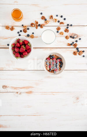 Müsli mit Beeren, Erdbeere, Walnüssen und Honig auf hölzernen Hintergrund Stockfoto