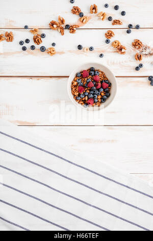 Draufsicht der Getreide mit Beeren, Nüssen und gestreiften Serviette auf hölzernen Hintergrund Stockfoto