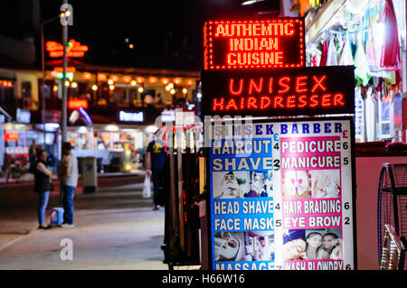 Geschäfte, Friseur, Bars und Restaurants in Hisaronu, Oludeniz, Fethiye, Türkei mit Neon und LED Schilder in der Nacht. Stockfoto