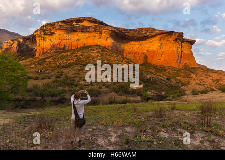 Touristen, die Abhaltung von Smartphone und nehmen Foto am malerischen Felsen durch Abendlicht in der majestätischen Golden Gate Highlands N beleuchtet Stockfoto