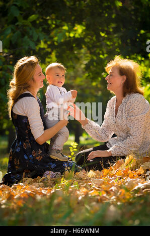Mutter umarmt ihr Sohn im Park mit Großmutter. Stockfoto