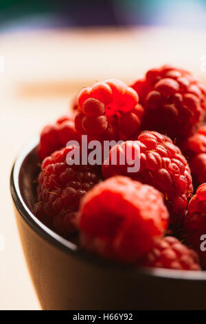 Himbeeren in einer Tasse auf einem unscharfen Hintergrund Holzbohlen. Stockfoto