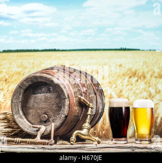 Gläser Bier und Ale Fass auf dem Holztisch. Handwerk-Brauerei. Im Bereich der Weizen auf dem Hintergrund. Stockfoto