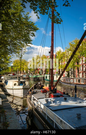 Strahlender Sonnenschein auf Hausbooten festgemacht an einem grünen Kanal in Amsterdam. Stockfoto