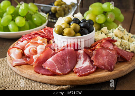 Antipasti Teller mit Speck, Trockenfleisch, Salami, Käse und Trauben auf einem hölzernen Hintergrund catering Stockfoto