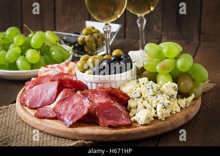 Antipasti Teller mit Speck, Trockenfleisch, Salami, Käse und Trauben auf einem hölzernen Hintergrund catering Stockfoto