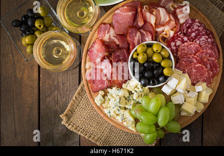 Antipasti Teller mit Speck, Trockenfleisch, Salami, Käse und Trauben auf einem hölzernen Hintergrund catering Stockfoto