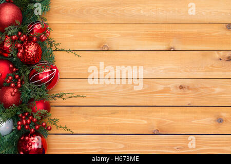 Bunte Rot Weihnachten Kranz umrandet mit Baumschmuck und Beeren in immergrünen Laub angeordnet, um die Seite am Cedar Holz Bo Stockfoto