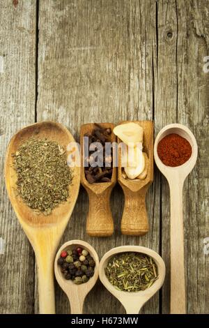 Holzlöffel zu würzen. Kräuter. Zimt und andere auf einem hölzernen rustikalen Hintergrund. Pfeffer. Große Sammlung von verschiedenen Gewürzen Stockfoto