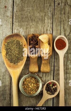 Holzlöffel zu würzen. Kräuter. Zimt und andere auf einem hölzernen rustikalen Hintergrund. Pfeffer. Große Sammlung von verschiedenen Gewürzen Stockfoto