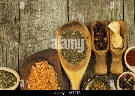 Holzlöffel zu würzen. Kräuter. Zimt und andere auf einem hölzernen rustikalen Hintergrund. Pfeffer. Große Sammlung von verschiedenen Gewürzen Stockfoto