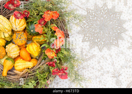 Bunter Herbst Herzstück mit ornamentalen Kürbisse oder Kürbisse und passenden orange Blumen und frisches Laub in einem Korb w Stockfoto