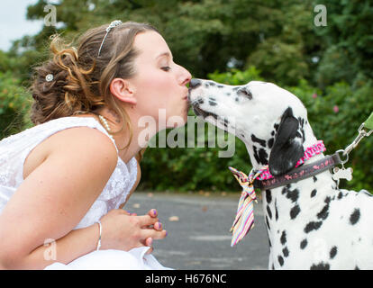 Schöne junge Braut reibt Nasen und Küsse mit ihrem treuen Hund Begleiter hat, am Tag ihrer Hochzeit. Hund hat Blei und Kragen Stockfoto