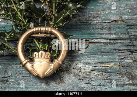 Claddagh und Holly Zweige irische Symbol der Liebe, Freundschaft und Loyalität im alten hölzernen Hintergrund Stockfoto