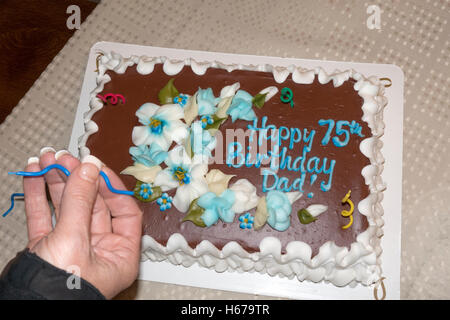 Tochter, platzieren dekorative Spirale Kerzen auf ihre Väter 75. Geburtstagskuchen. Champlin Minnesota MN USA Stockfoto