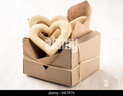 Geschenk-Box gefüllt mit hausgemachten Herzkekse zum Valentinstag auf weißer Holztisch Stockfoto