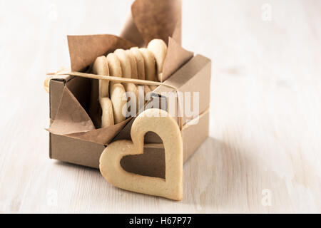 Geschenk-Box gefüllt mit hausgemachten Herzkekse zum Valentinstag auf weißer Holztisch Stockfoto