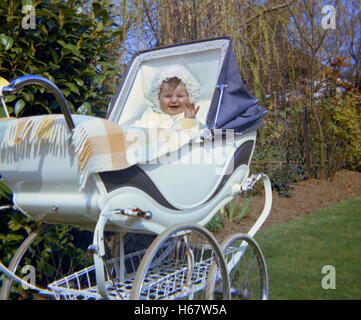 kleines Kind sitzt in einem alten Stil Kinderwagen England der 1970er Jahre Stockfoto