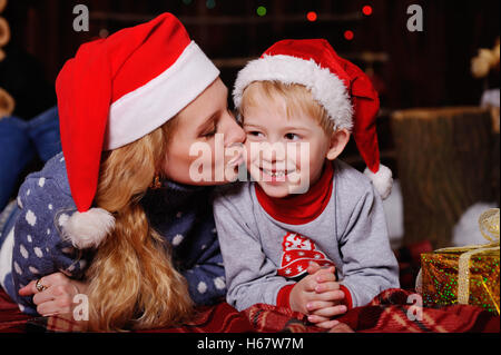 Mama und Baby in Rot Weihnachten Kappen auf ein kariertes liegend Stockfoto