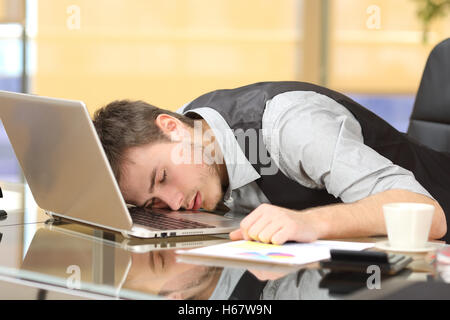 Müde, überarbeitet Geschäftsmann über einen Laptop in einem Schreibtisch bei der Arbeit in seinem Büro schlafen Stockfoto