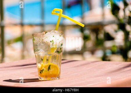 Mojito mit gelben Stroh auf dem Tisch eines Hotels in hellem Sonnenlicht während des Urlaubs Stockfoto