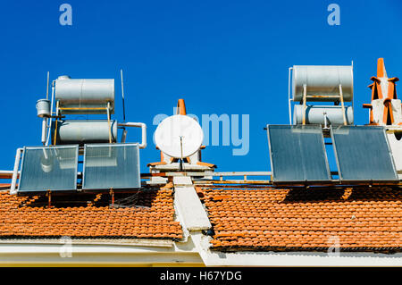 Solare Wasser-heizungen und Satellitenschüsseln auf dem Dach eines Gebäudes in einem heißen Klima Stockfoto