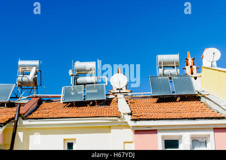 Solare Wasser-Heizungen und Satellitenschüsseln auf dem Dach eines Gebäudes in einem heißen Klima. Stockfoto