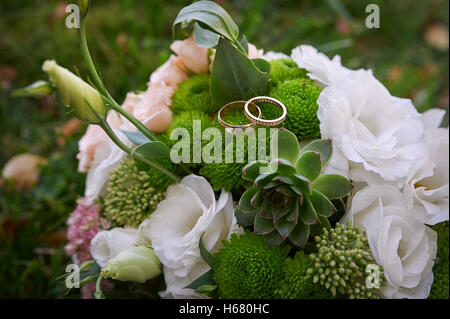 zwei goldene Ringe auf eine Braut Hochzeit bouquet Stockfoto