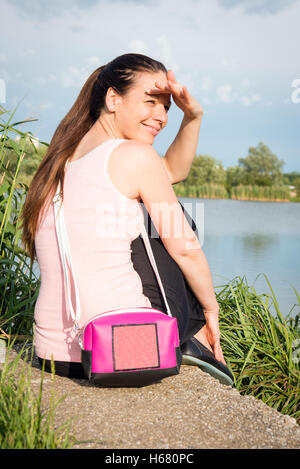 Porträt der jungen Dame in rosa t-Shirt mit Handtasche Standortwahl am See Stockfoto