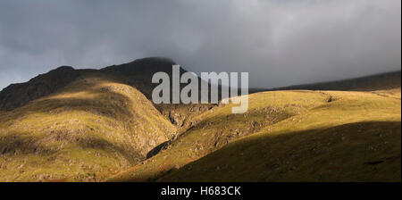 Regenwolke bilden dichten Nebels Abstieg vom steilen Berghang Badeort im Abendlicht, Glen Coe, Schottisches Hochland, Schottland Stockfoto