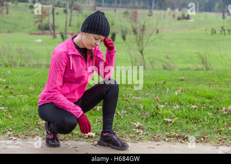 Junge Sportlerin Gefühl, Benommenheit oder mit Kopfschmerzen an einem kalten Wintertag in den Spuren von einem städtischen Park. Stockfoto