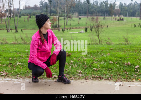 Junge Sportlerin analysieren die Strecke vor der Ausführung an einem kalten Wintertag in einem städtischen Park. Stockfoto