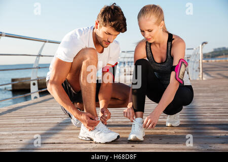 Draufsicht der junge Mann und Frau, die Schnürsenkel zu binden, während im Freien stehen Stockfoto