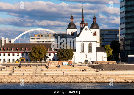 eutschland, Köln, Blick über den Rhein der Kirche Alt St. Heribert, im Hintergrund der Bogen von der Lanxess-Arena. Stockfoto