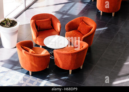 Orangefarbene Stühle und Tisch in einer Hotellobby Stockfoto