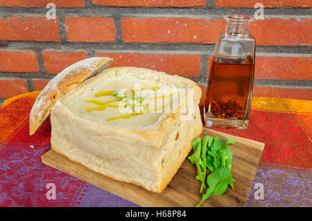 Traditionelle deutsche pikanten Knoblauchsuppe serviert in einem geschnitzten, Laib Brot Stockfoto