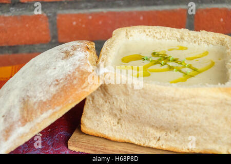 Traditionelle deutsche pikanten Knoblauchsuppe serviert in einem geschnitzten, Laib Brot Stockfoto