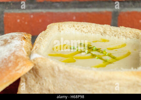 Traditionelle deutsche pikanten Knoblauchsuppe serviert in einem geschnitzten, Laib Brot Stockfoto