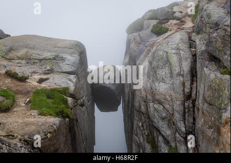 Kjerag-Stein, an der Steilküste zwischen zwei hohen Felsen hängen. Stockfoto