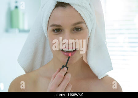 Frau Anwendung Lipgloss auf den Lippen in Bad Stockfoto