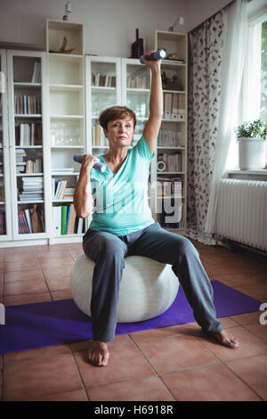 Ältere Frau Training mit Hanteln auf Gymnastikball Stockfoto
