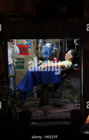 Ein Mann hat einen neuen Haarschnitt im Ladengeschäft Straße, ein Nachtleben in Bangkok in den Tagen nach dem Tod von König Rama IX. Stockfoto